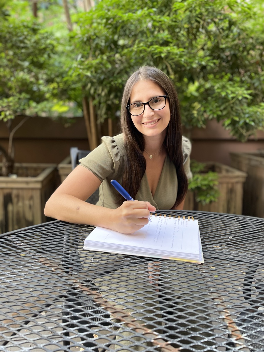 Brianna Greenspan writing in a journal at a garden table