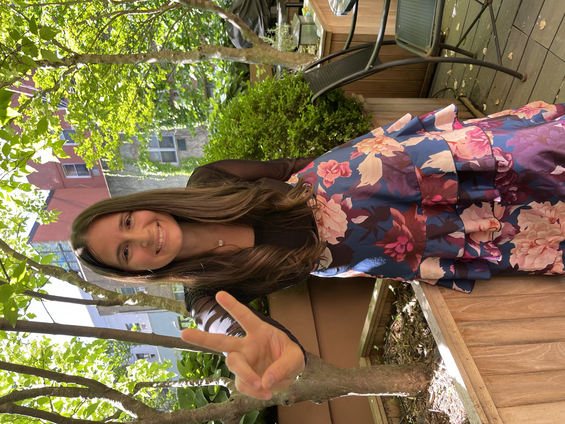 Brianna Greenspan in a floral dress, joyful in a sunlit garden