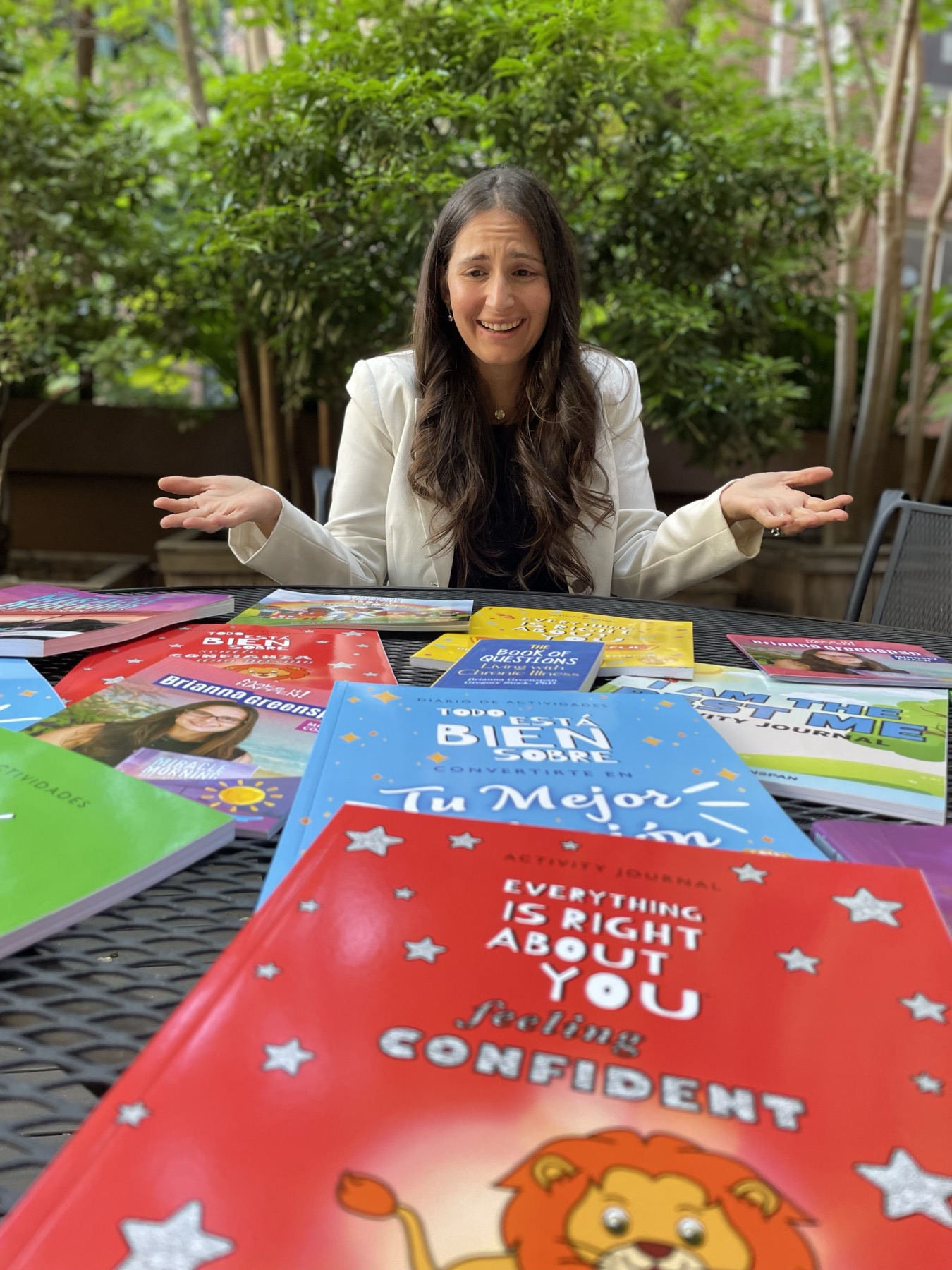 Brianna with her arms outstretched, surrounded by her colorful Everything Is Right About You books